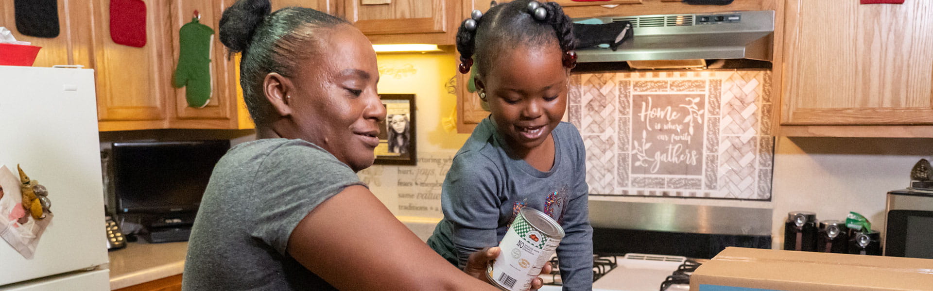 Una madre y su hija sostienen alimentos en una cocina