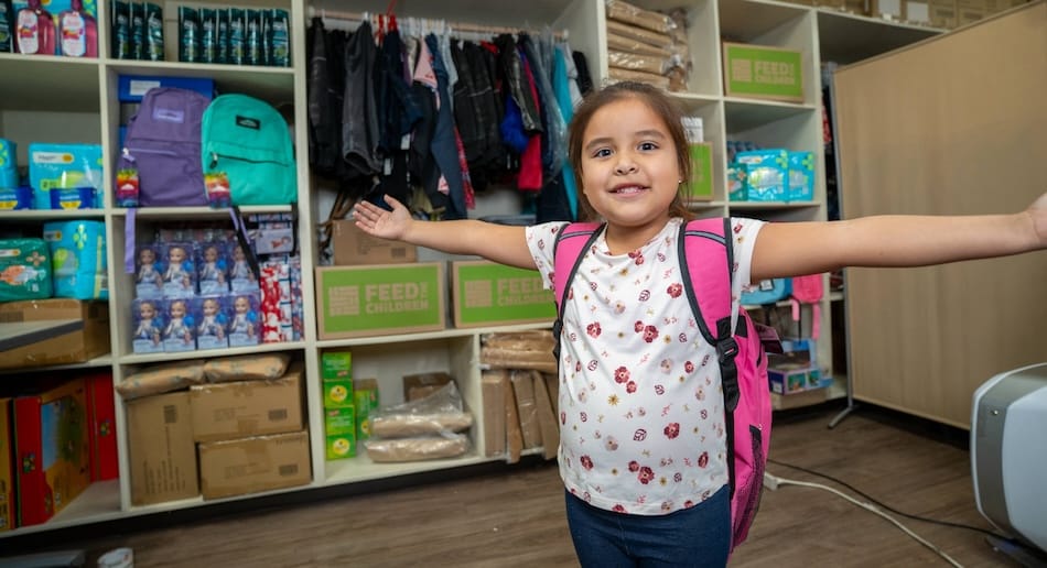 A child spreading their arms standing in front of school supplies