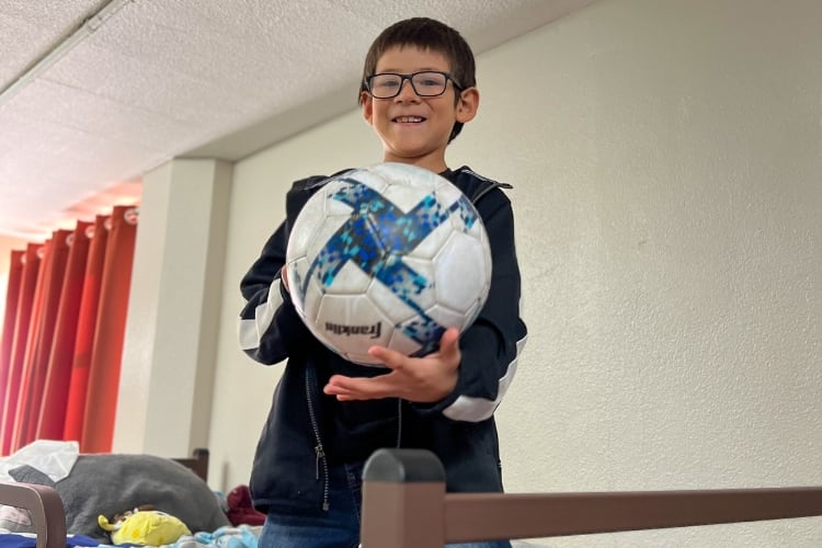 El hijo de Lily sosteniendo una pelota en la cama