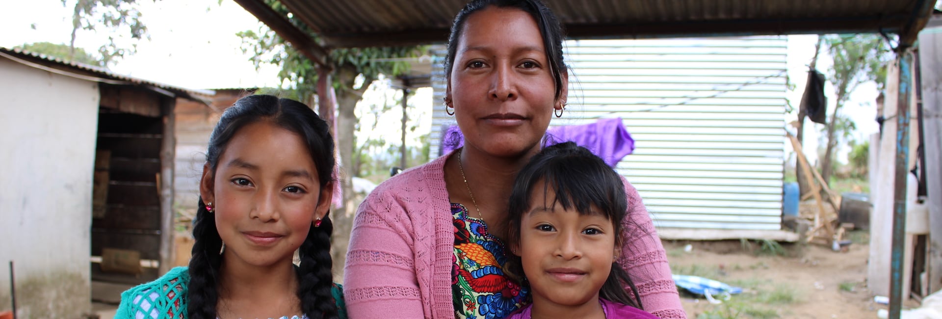 Una mujer y sus dos hijos sentados al aire libre