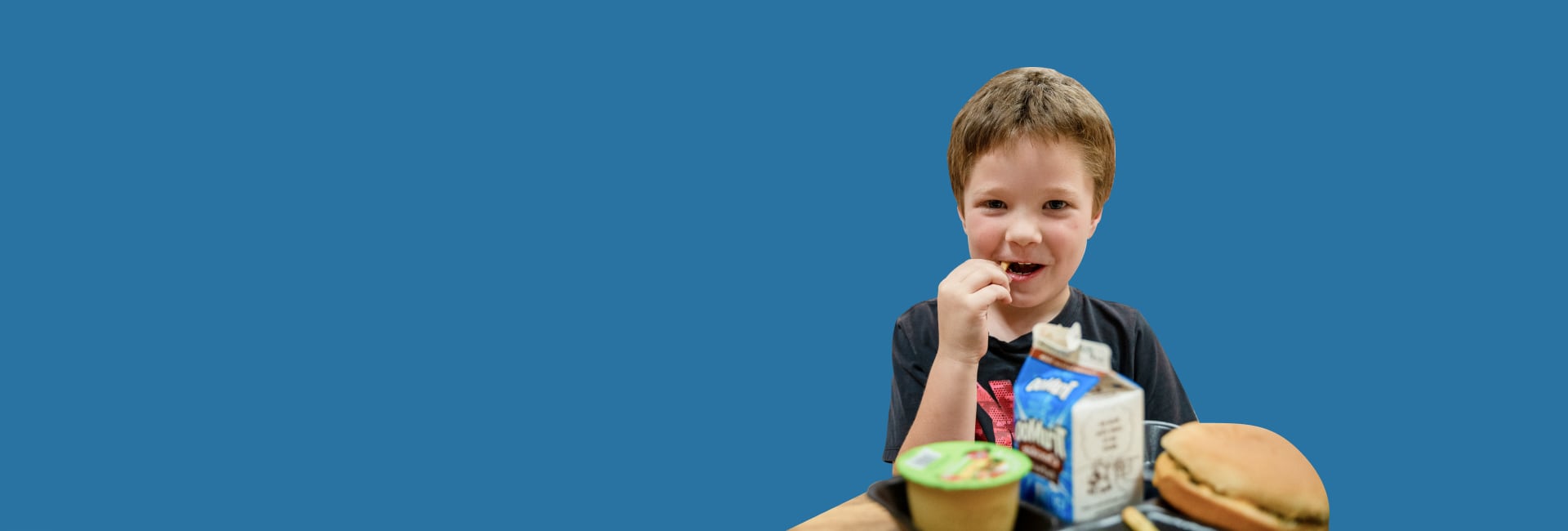 Un niño con comida delante de un fondo azul